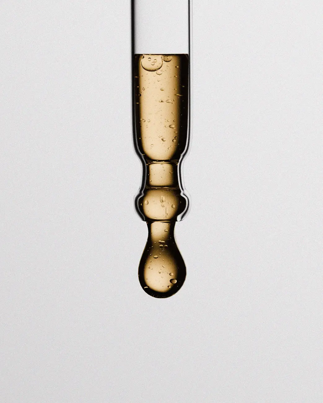close-up of uuanted natural tone lip serum dropper with golden formula